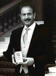 Pete Rana Holding MBE Award From Her Majesty The Queen