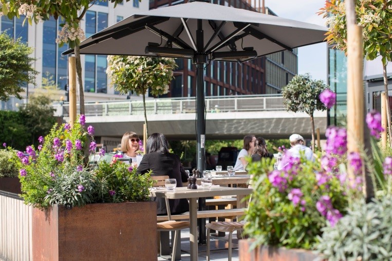 People sat at tables outside pub in city centre setting